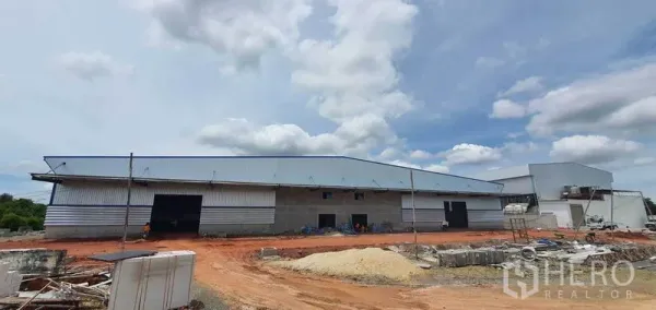 โรงงาน ให้เช่าในMueang Samut Sakhon, Samut Sakhon - ภายนอกโรงงานกรุผนังเมทัลชีทพร้อมช่องโหลดสินค้าและลานดินกว้าง ใต้ท้องฟ้ามีเมฆในสมุทรสาคร