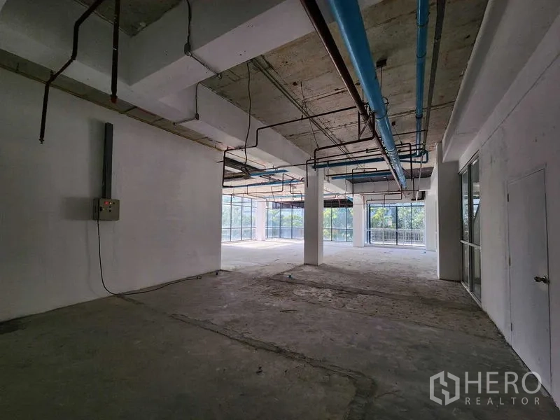 零售空间 出租在Sathon, Bangkok - 开放式零售区域，大片窗户与蓝色顶置管道，原始混凝土地面