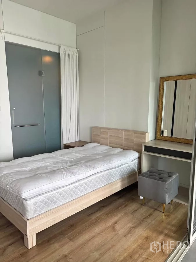 Condominium for rent or sale in Phaya Thai, Bangkok - Bright bedroom with light wood bed, dressing table, mirror, and cushioned stool.