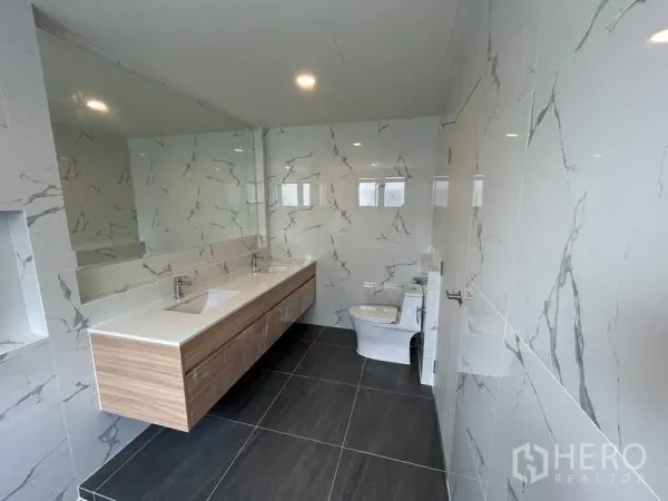 Detached House for rent in Bang Phli, Samut Prakan - Large bathroom with double vanity, marble-effect tiles and dark floor.