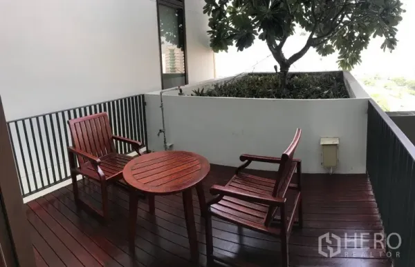 公寓 出租在Pathum Wan, Bangkok - 私密阳台，木质圆桌与椅子，旁设绿植花槽