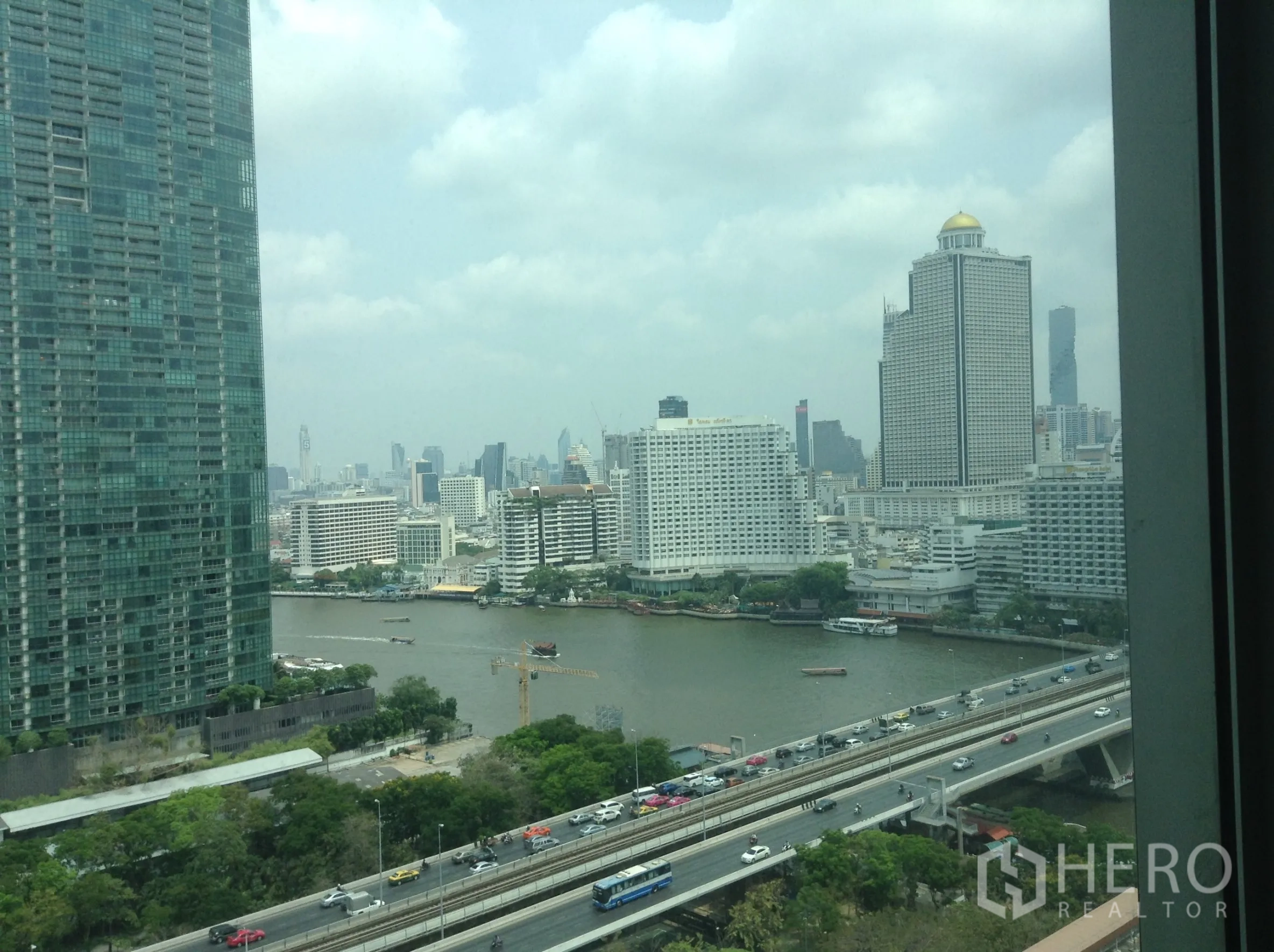 公寓 出租或出售在Khlong San, Bangkok - 从公寓窗户俯瞰湄南河与曼谷天际线的高层景观。