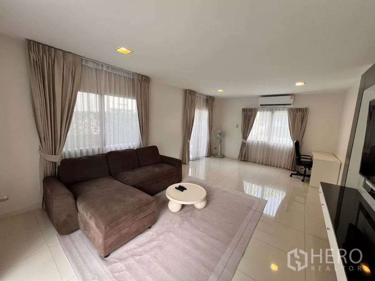 独立式住宅 出租在Lat Krabang, Bangkok - 宽敞客厅，多扇窗户、空调与工作桌。