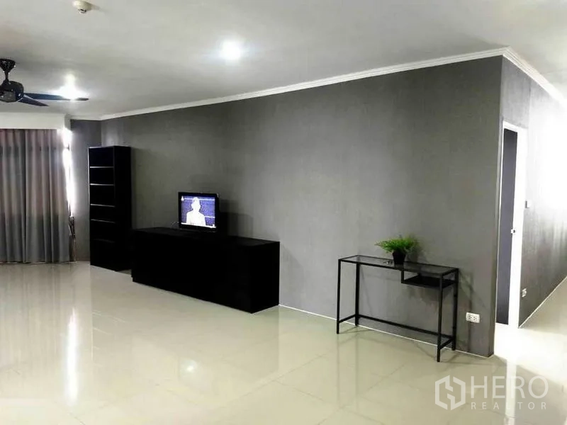 公寓 出租在Watthana, Bangkok - 极简客厅，灰色墙面与亮面地砖，电视柜、置物架和吊扇