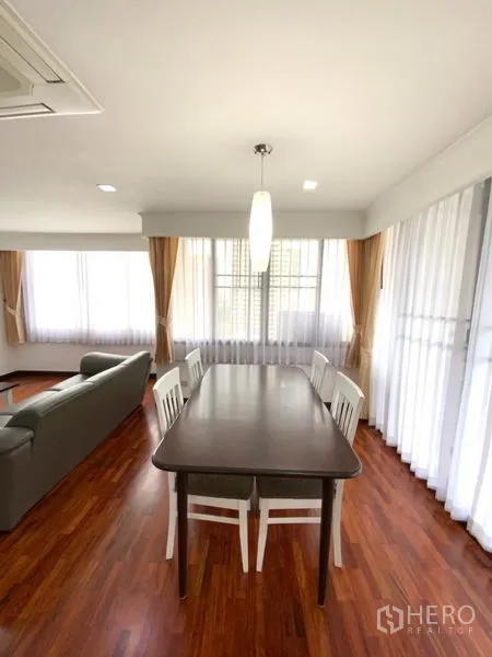 公寓 出租在Watthana, Bangkok - 四人餐桌临落地窗，纱帘与吊灯营造通透用餐氛围。