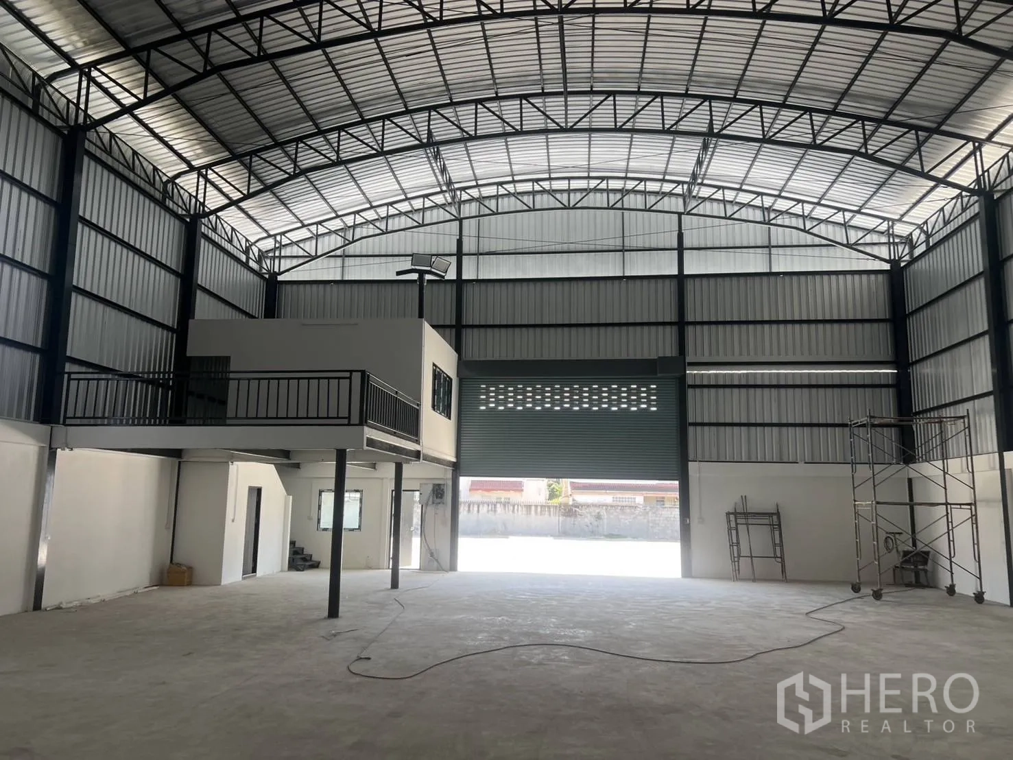 仓库 for rent in Bang Phli, Samut Prakan - 面向宽大的卷闸门入口，旁边为夹层办公室与脚手架。