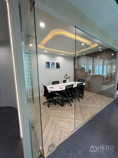 Office Space for rent - Glass-enclosed meeting room with six chairs and cove lighting over herringbone floor.