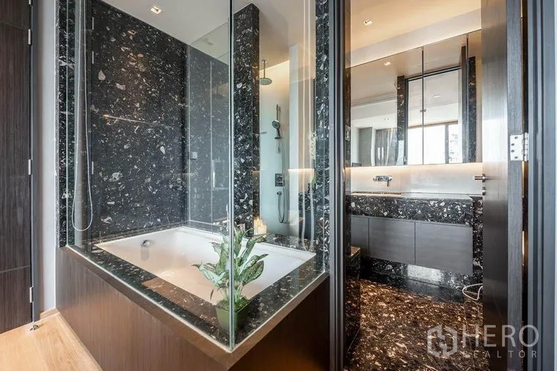Condominium for rent in Khlong Toei, Bangkok - Luxurious bathroom with black marble tub and glass shower enclosure