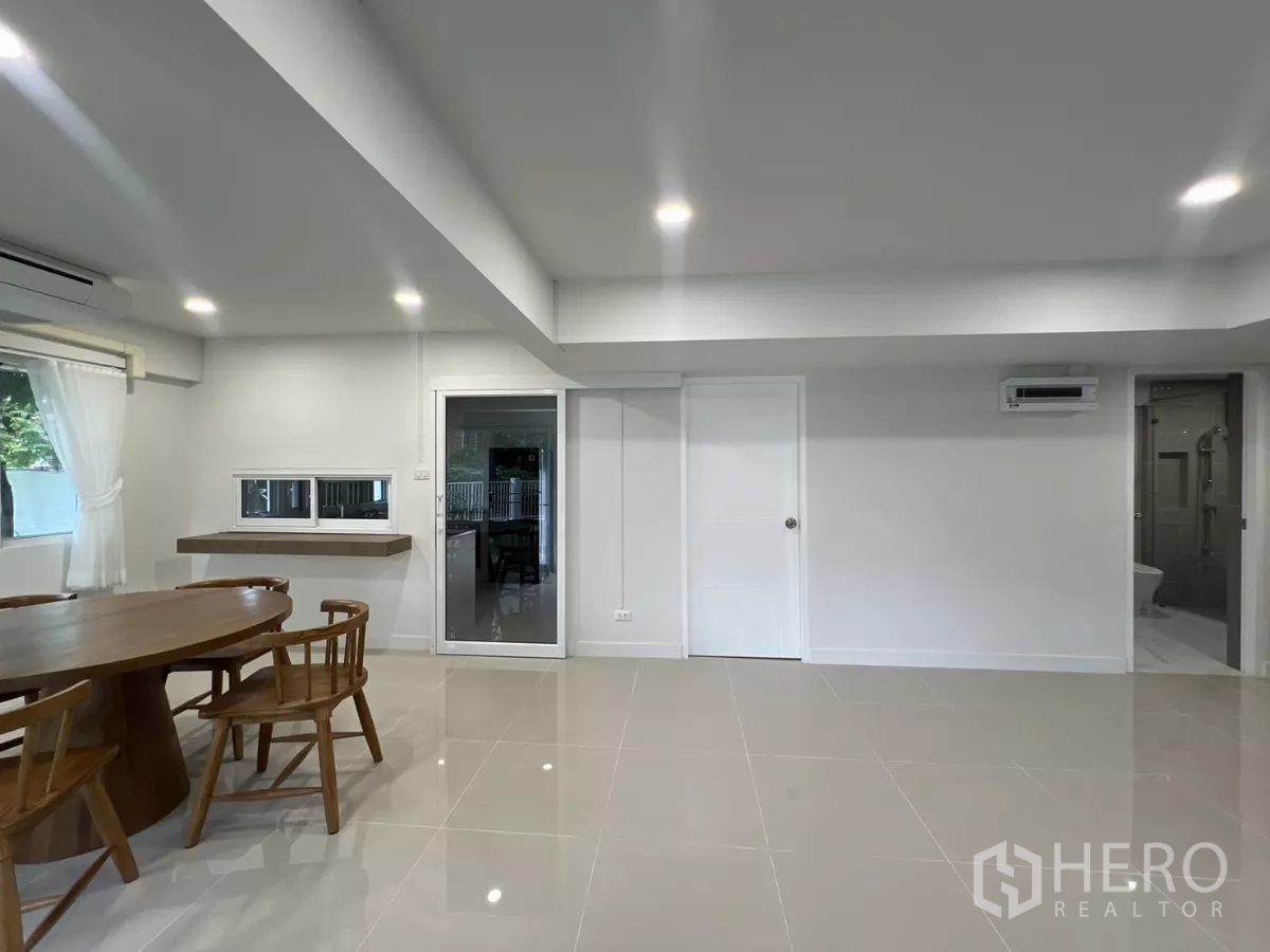 Detached House for rent in Saphan Sung, Bangkok - Dining zone with round wooden table next to sliding doors and nearby bathroom.