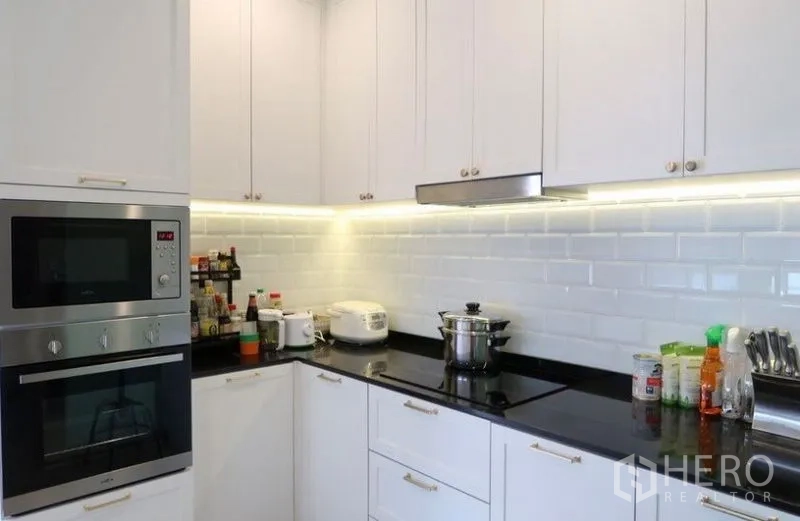 Detached House for rent or sale in Saphan Sung, Bangkok - European-style kitchen with built-in oven, cooktop, subway tile backsplash, and lighting.