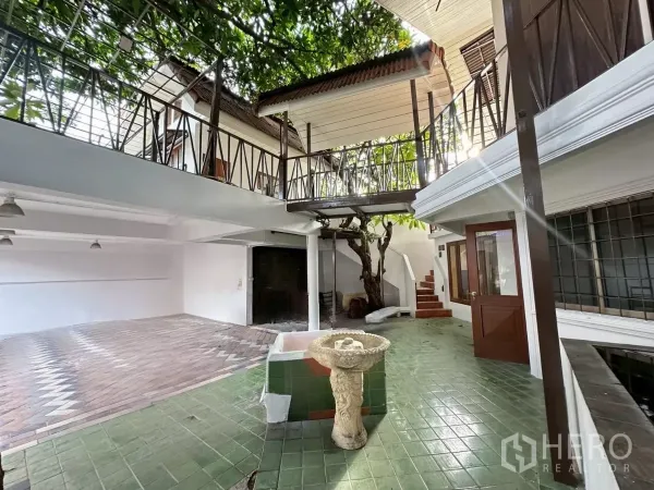 Home Office for rent in Lat Phrao, Bangkok - Shaded open-air courtyard with green tiles, balcony walkways and a mature tree