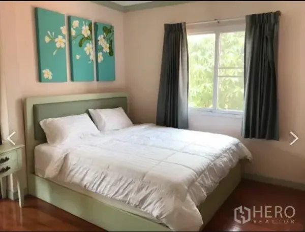 Detached House for sale in Saphan Sung, Bangkok - Bright bedroom with double bed, window, curtains and floral wall art.