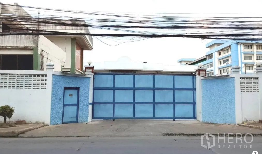 Factory for rent or sale in Bang Phli, Samut Prakan - Wide blue sliding gate and secure perimeter wall of the factory compound.