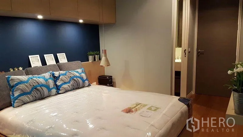 公寓 出租在Khlong San, Bangkok - 温馨卧室，蓝色特色墙与射灯，通向套内卫浴
