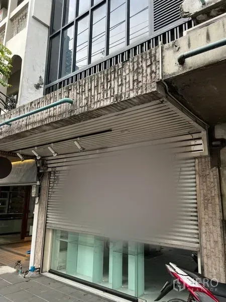 店屋 出租在Bang Rak, Bangkok - 店屋外立面，金属卷帘与玻璃门面，临街人行道。