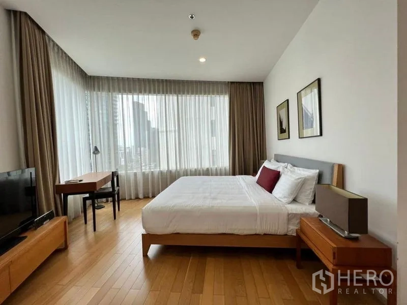 公寓 出租在Khlong Toei, Bangkok - 主卧配大床与书桌，大幅窗户采光充足，享城市景观。