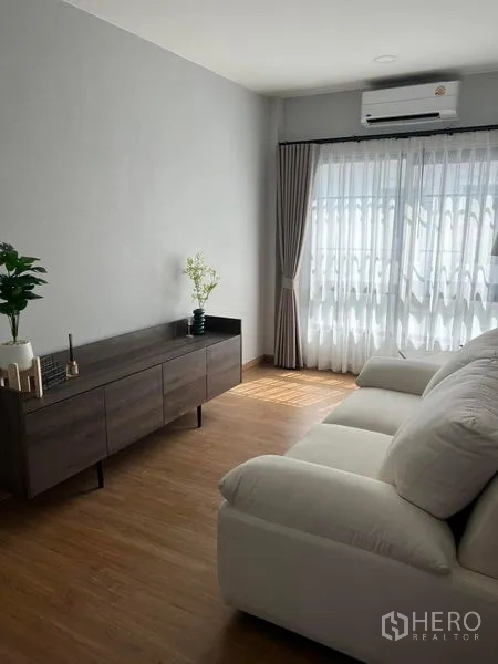 独立式住宅 出租在Bang Phli, Samut Prakan - 小客厅，白色沙发、矮柜并连接露台的滑门。