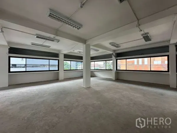 Office Space for rent in Watthana, Bangkok - Bright empty office space with wrap-around windows, structural columns, and fluorescent ceiling lights.