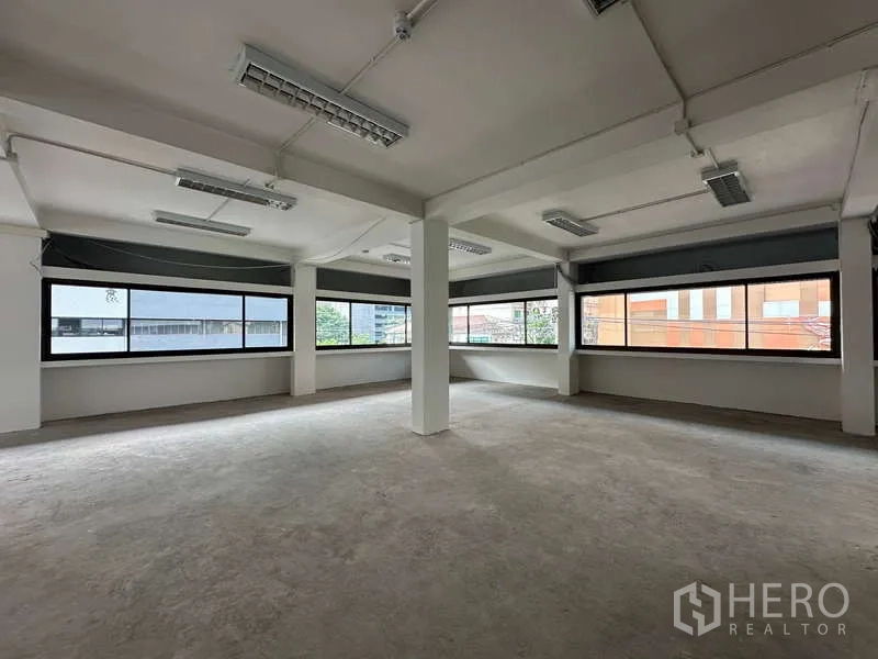 Office Space for rent in Watthana, Bangkok - Bright empty office space with wrap-around windows, structural columns, and fluorescent ceiling lights.