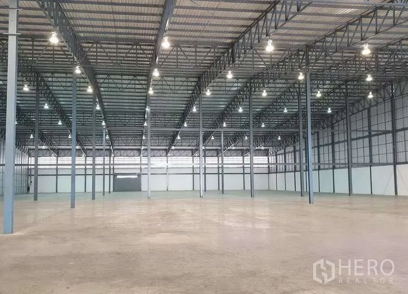 Warehouse for rent in Mueang Samut Prakan, Samut Prakan - Open storage hall showing grid of steel columns and smooth concrete surface.
