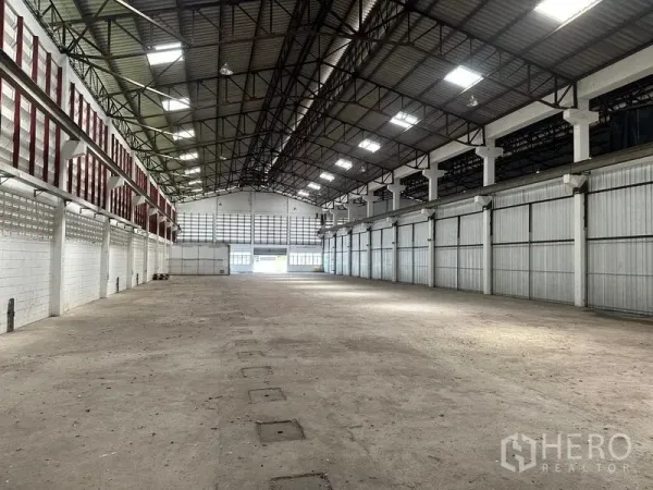 Warehouse for rent in Lam Luk Ka, Pathum Thani - Open warehouse floor facing multiple bays, steel roof with lighting panels, and durable concrete surface.