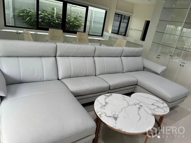 Detached House for sale in Saphan Sung, Bangkok - Close-up of gray L-shaped sofa with round marble nesting tables.
