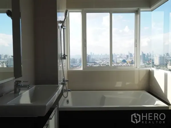 公寓 出租在Yan Nawa, Bangkok - 浴室设大浴缸，宽窗可看曼谷天际线与河景，并配洗手台。