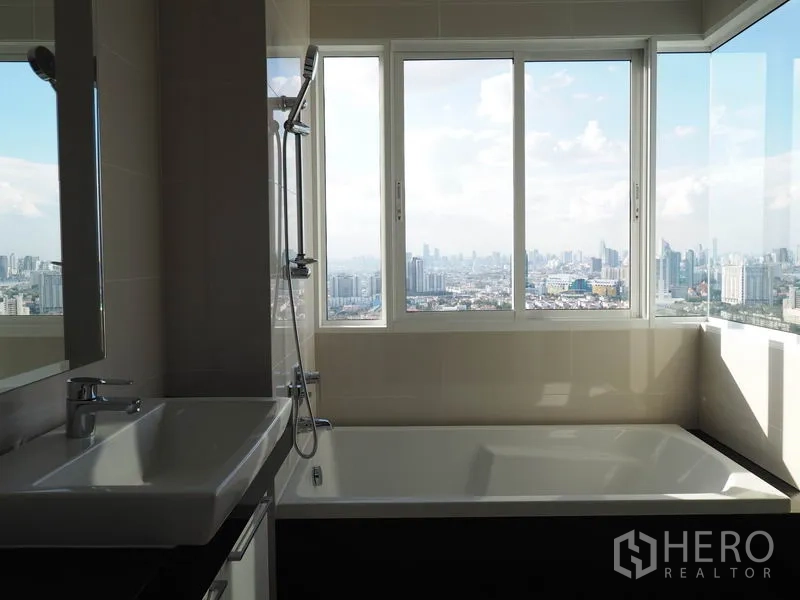 公寓 出租在Yan Nawa, Bangkok - 浴室设大浴缸，宽窗可看曼谷天际线与河景，并配洗手台。