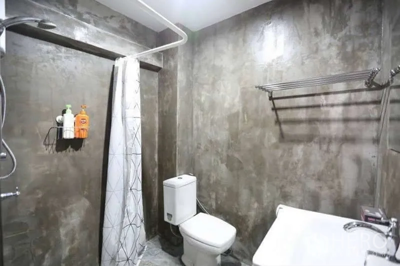 Home Office for rent in Khlong Toei, Bangkok - Modern bathroom with cement walls, walk-in shower, toilet, and vanity.