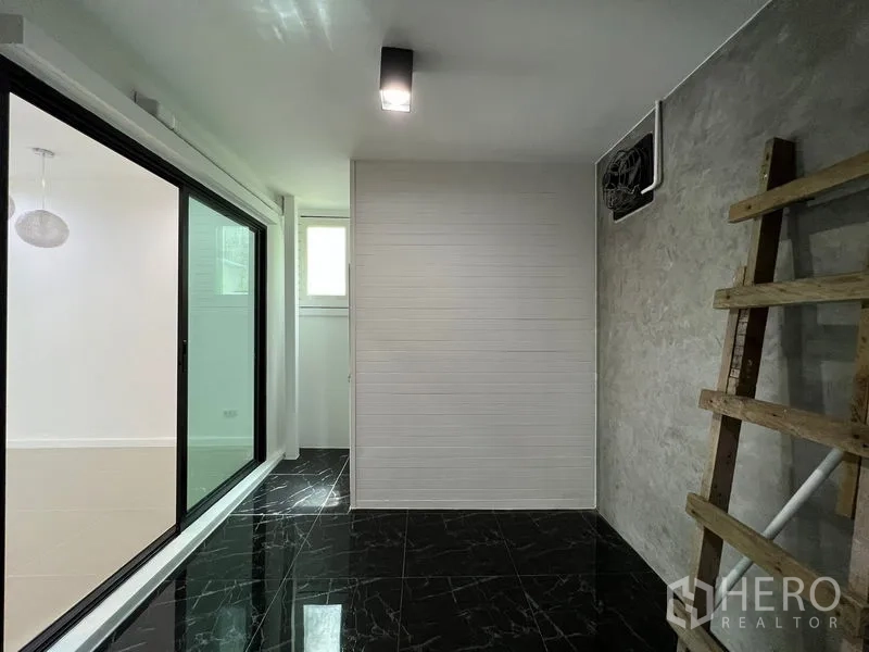 Townhouse for sale in Bang Kapi, Bangkok - Rear utility area with black tiled floor and sliding glass partition.