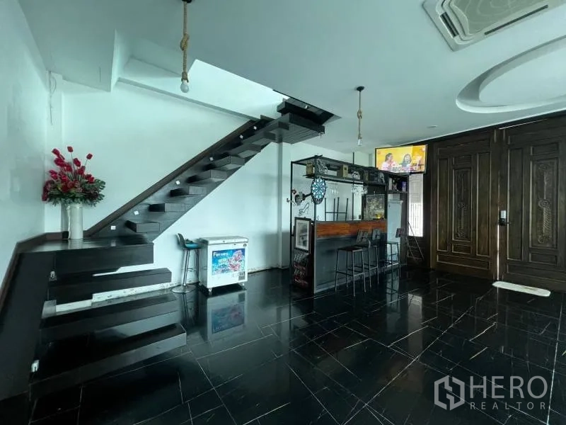 独立式住宅 出售在Lat Phrao, Bangkok - 大厅带吧台、悬浮楼梯与雕花木质大门。