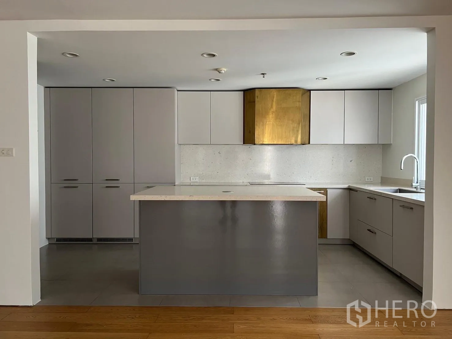 Condominium for rent or sale in Sathon, Bangkok - Contemporary U-shaped kitchen with island, matte cabinetry and brass hood accent.