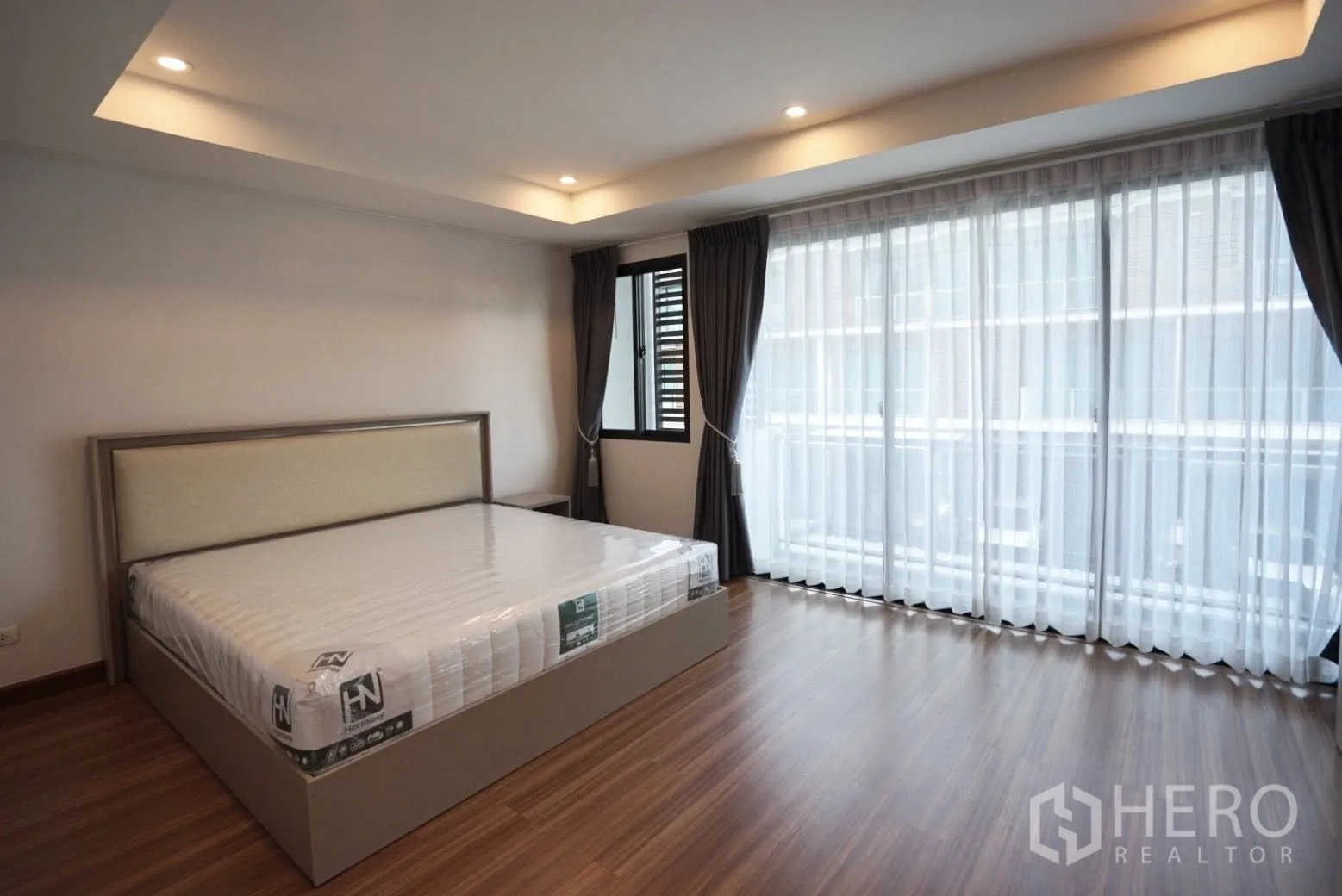 Townhouse for rent in Bang Kapi, Bangkok - Large master bedroom with cove lighting, king bed and a wall of full-height windows.