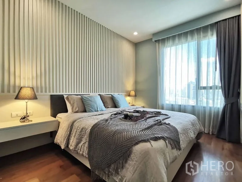 Condominium for rent in Sathon, Bangkok - Master bedroom with feature slat wall, bedside lamps and a large window.