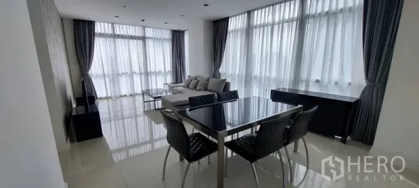 公寓 出租在Pathum Wan, Bangkok - 采光充足的客餐厅，一整面落地窗与纱帘，亮面地砖，黑色餐桌椅与沙发的曼谷公寓。