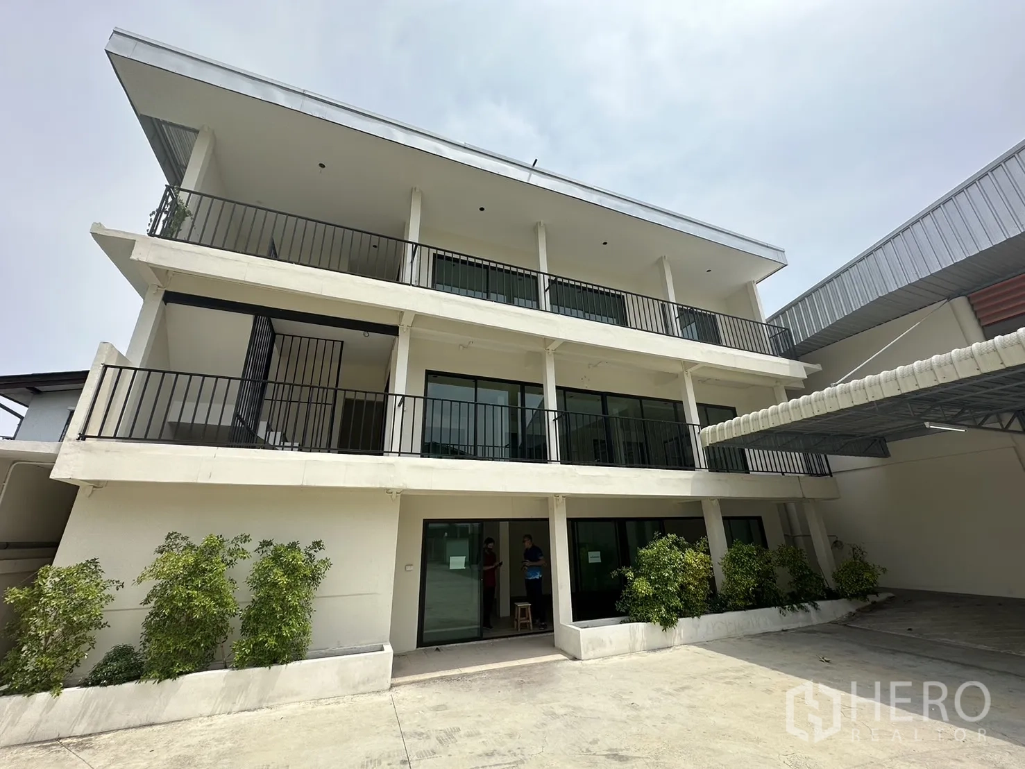 Warehouse for rent in Suan Luang, Bangkok - Modern three-storey office facade with balconies and greenery.
