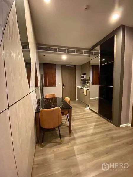Condominium for rent in Phra Khanong, Bangkok - Dining nook and entry corridor facing a compact kitchenette and mirrored feature wall.