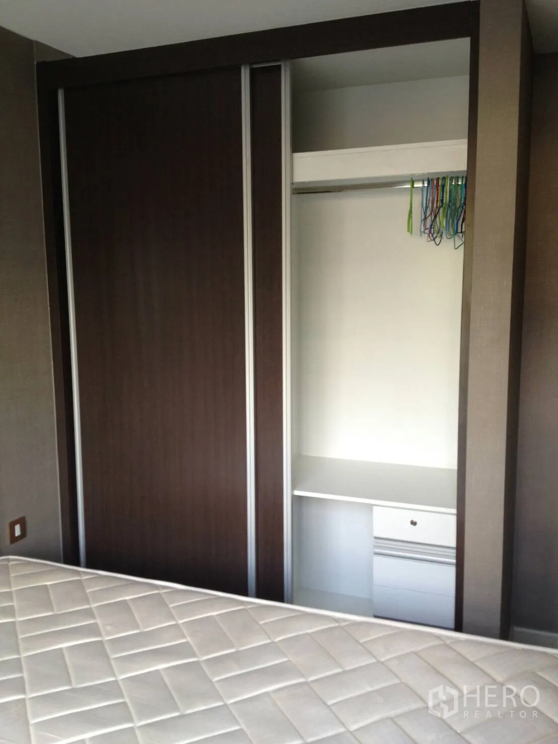 Condominium for rent in Khlong Toei, Bangkok - Built-in wardrobe with sliding dark wood doors, shelving and drawers.
