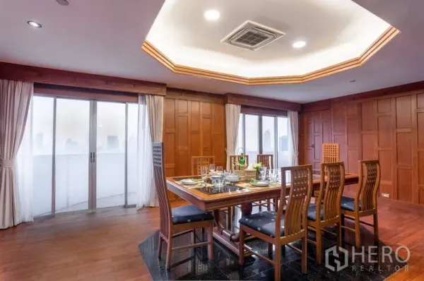 Condominium for rent or sale in Ratchathewi, Bangkok - Dining room for eight with recessed ceiling, wood walls and sliding doors to a city-view balcony.