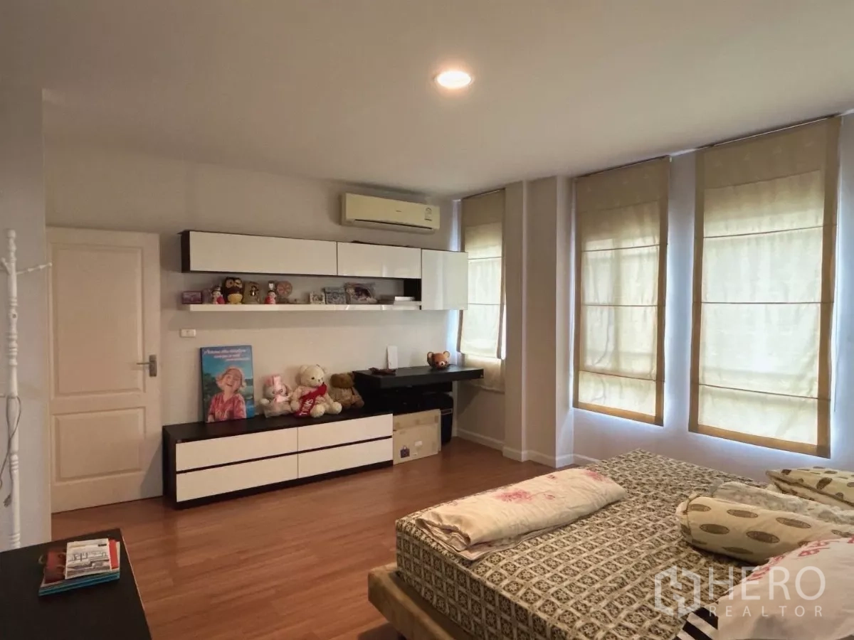 Detached House for sale in Bang Kapi, Bangkok - Master bedroom wall with built-in shelves, desk, and air conditioning unit.