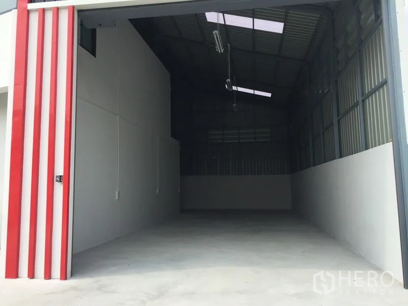 货栈 出售在Khlong Luang, Pathum Thani - 红色框架的大型卷帘门通向宽敞仓库。