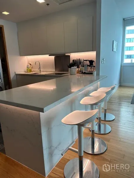 Condominium for rent in Khlong Toei, Bangkok - Close-up of marble island and minimalist kitchen with under-cabinet lighting.
