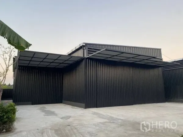 Warehouse for rent in Wang Thonglang, Bangkok - Side view of the warehouse showing extended canopy and wide driveway for truck access.