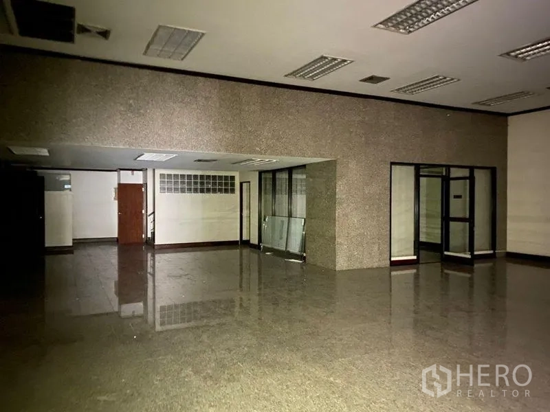 Retail Space for rent - Large hall with polished stone floor, glass partitions and drop ceiling lighting.
