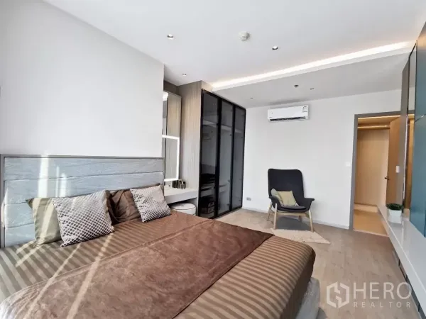 公寓 出租在Watthana, Bangkok - 宽敞主卧设玻璃衣柜、休闲椅与空调。