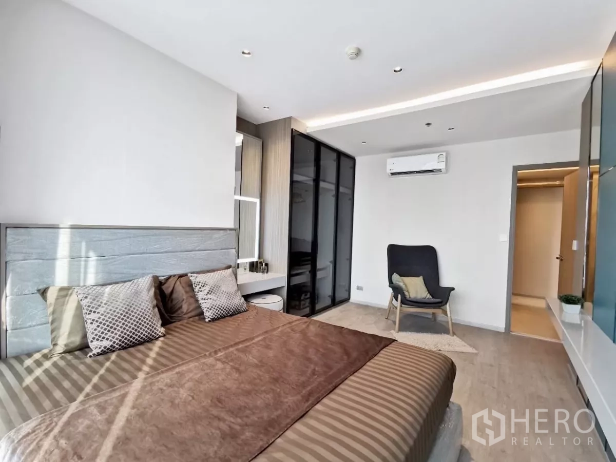 公寓 出租在Watthana, Bangkok - 宽敞主卧设玻璃衣柜、休闲椅与空调。