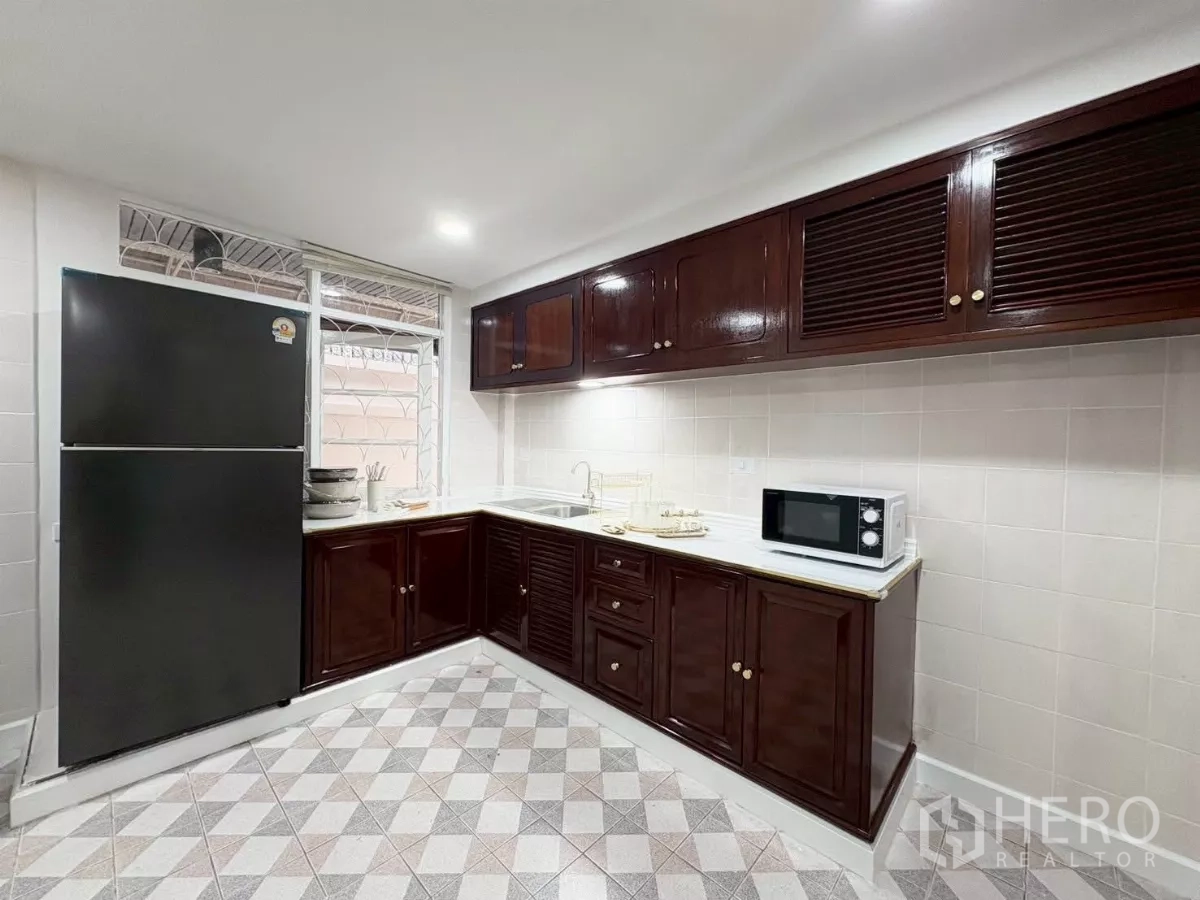 Detached House for rent in Huai Khwang, Bangkok - Fitted kitchen with L‑shaped cabinetry, fridge and microwave