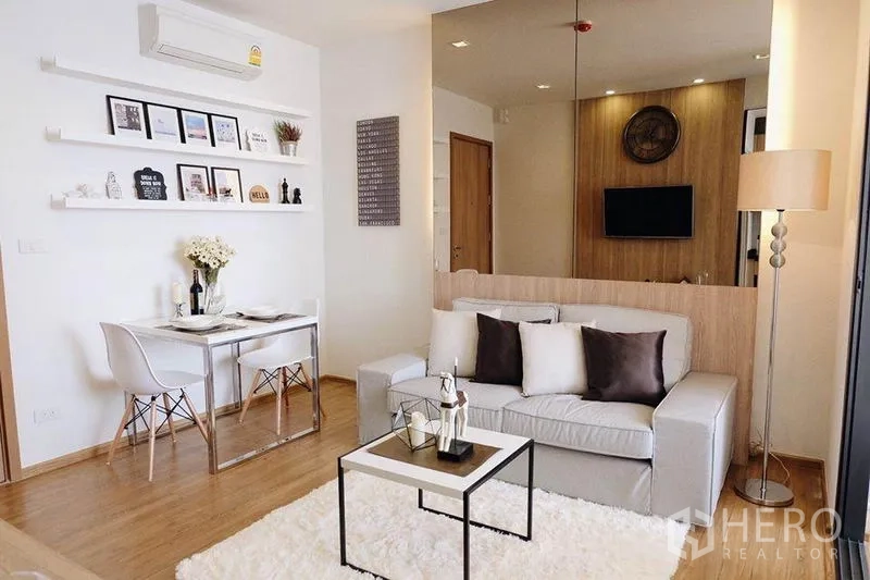 Condominium for sale in Watthana, Bangkok - Open‑plan living and dining area with sofa, rug, coffee table and two‑seat dining.