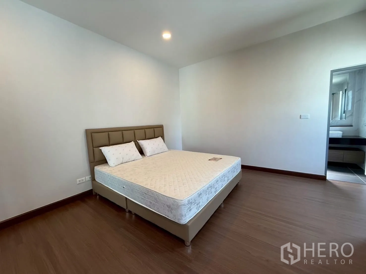 Townhouse for rent - Bedroom leading to an ensuite bathroom with wood flooring and padded headboard.