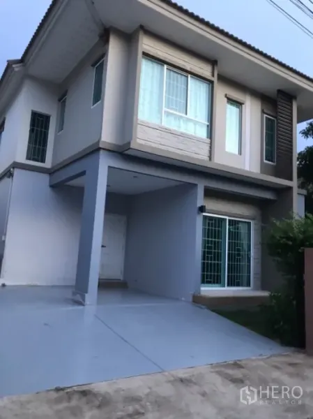 Detached House for rent in Saphan Sung, Bangkok - Front view with covered carport, driveway and large sliding glass doors.